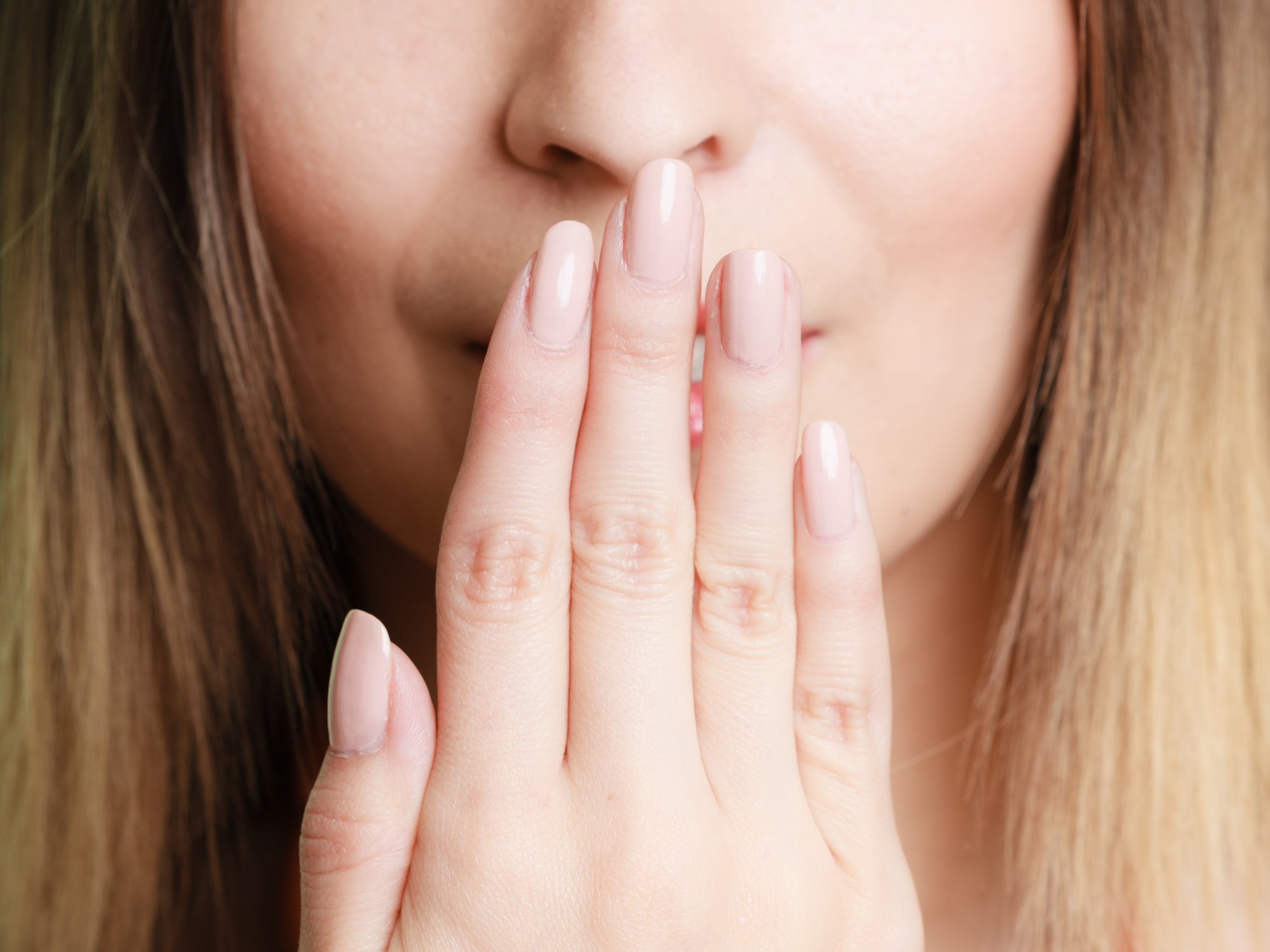 close up of woman with hand over mouth