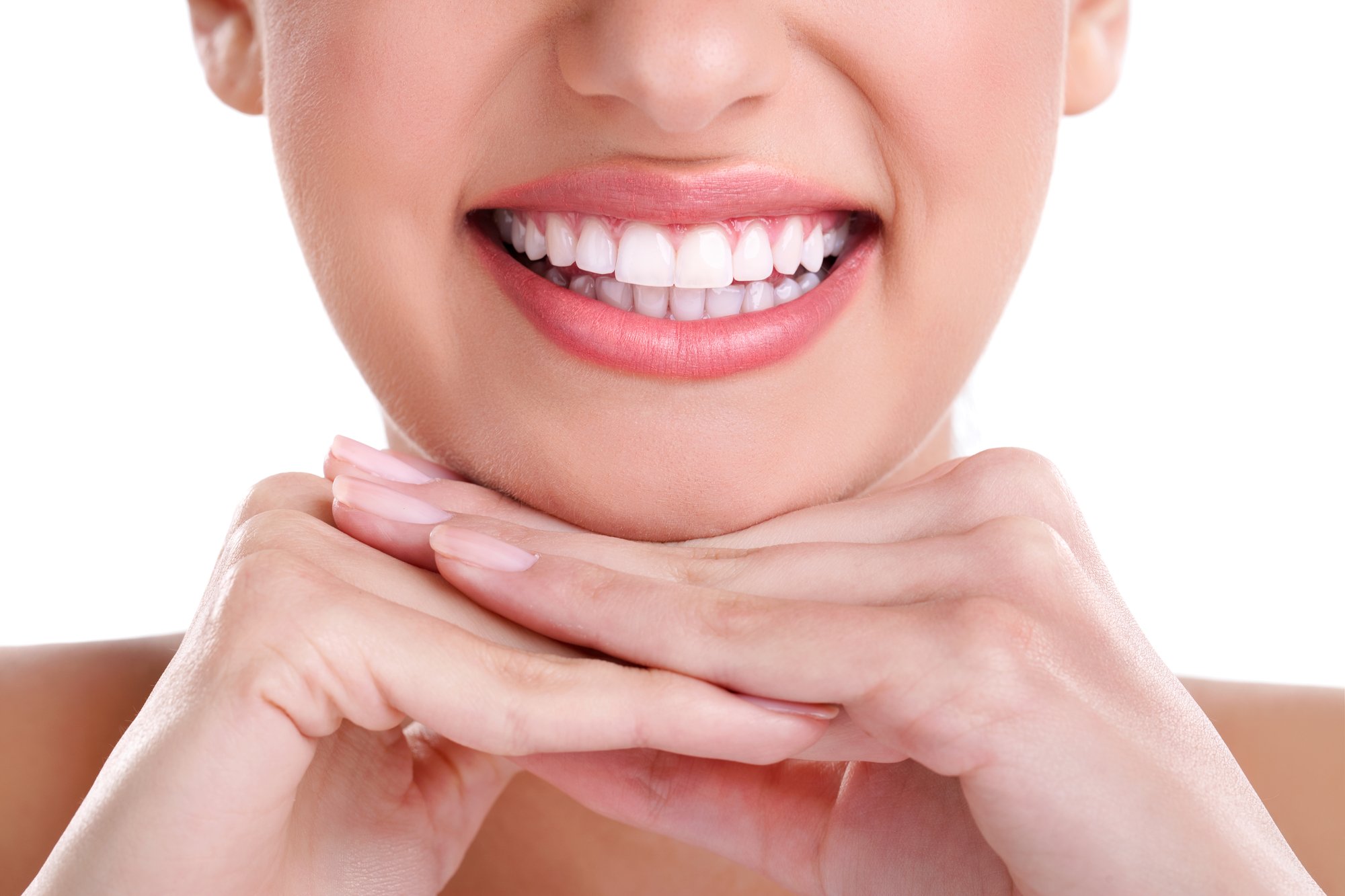 A person rests their chin on their hands and smiles widely to reveal the benefits of routine oral hygiene