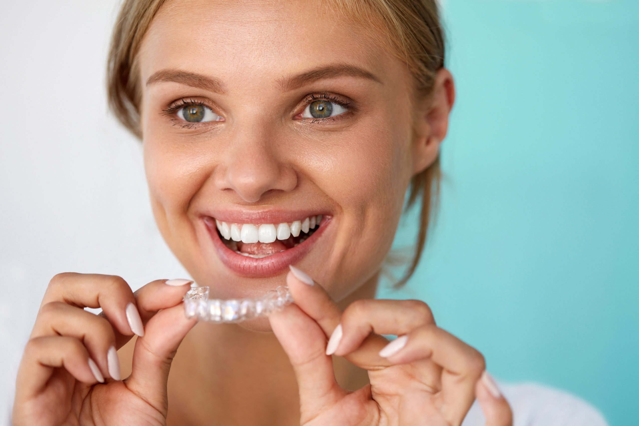 Smiling woman holding Invisalign tray