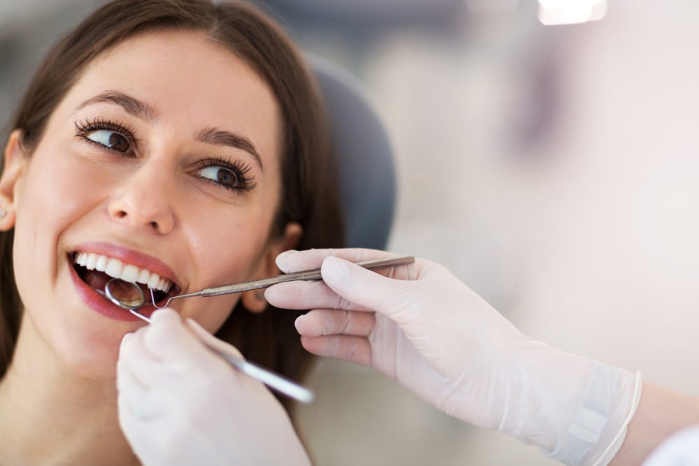 woman smiling and receiving dental checkup from gentle dentist