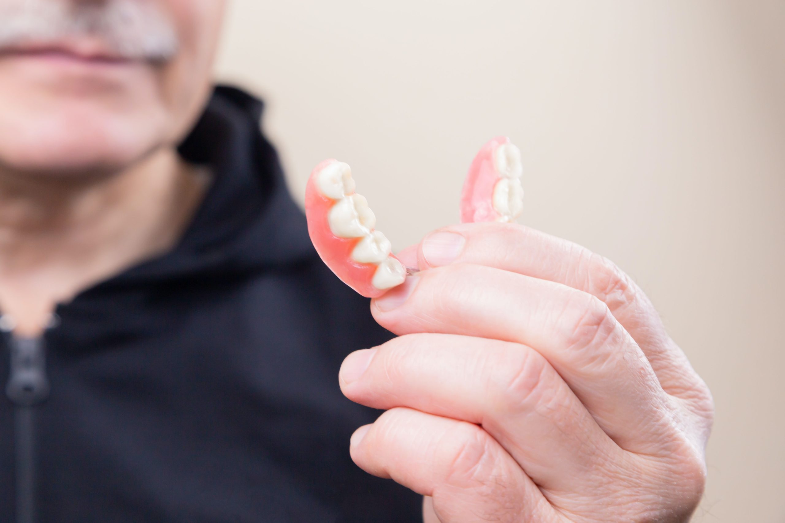 Man holds partial dentures in his hand