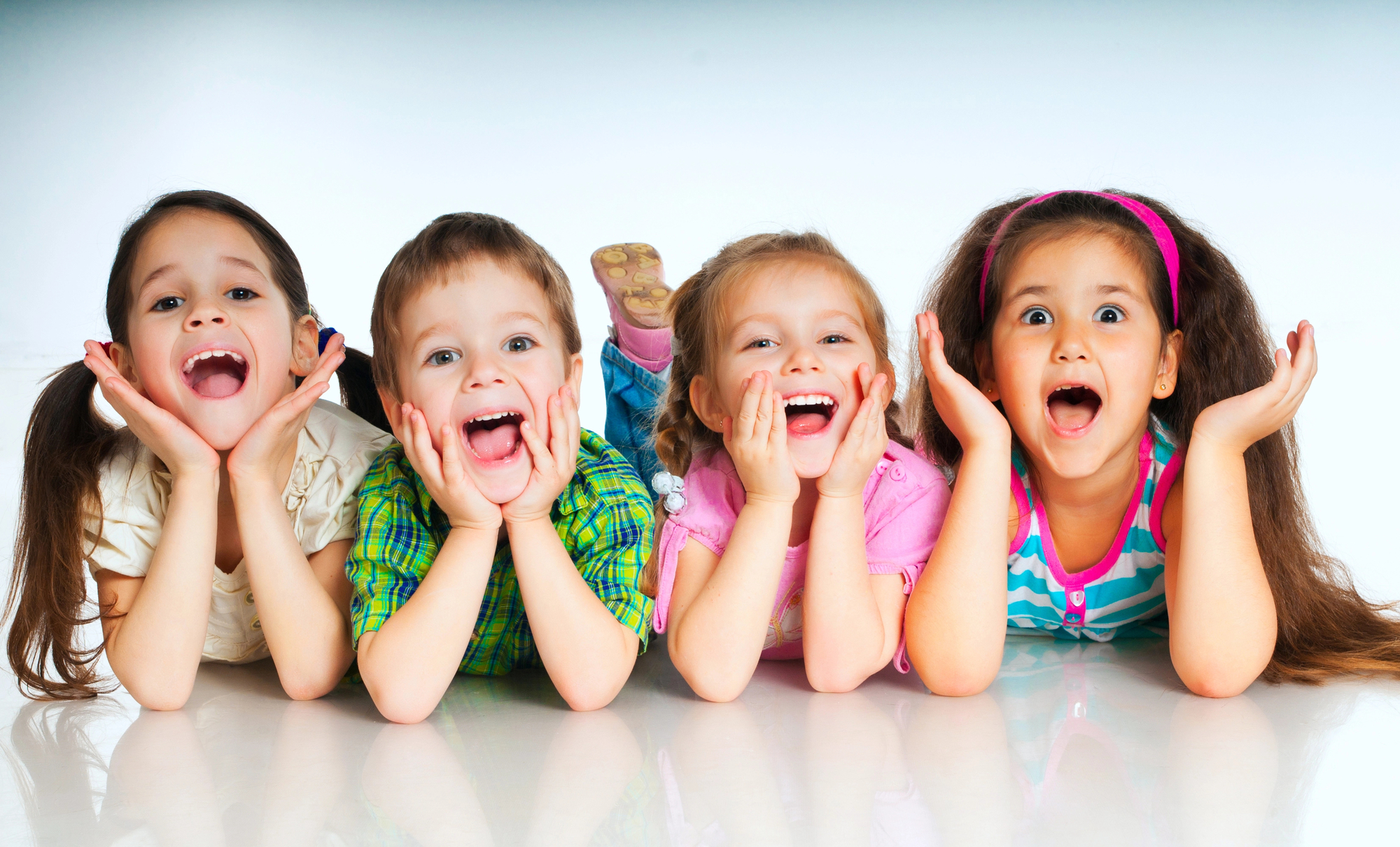 portrait of four children laying on floor smiling