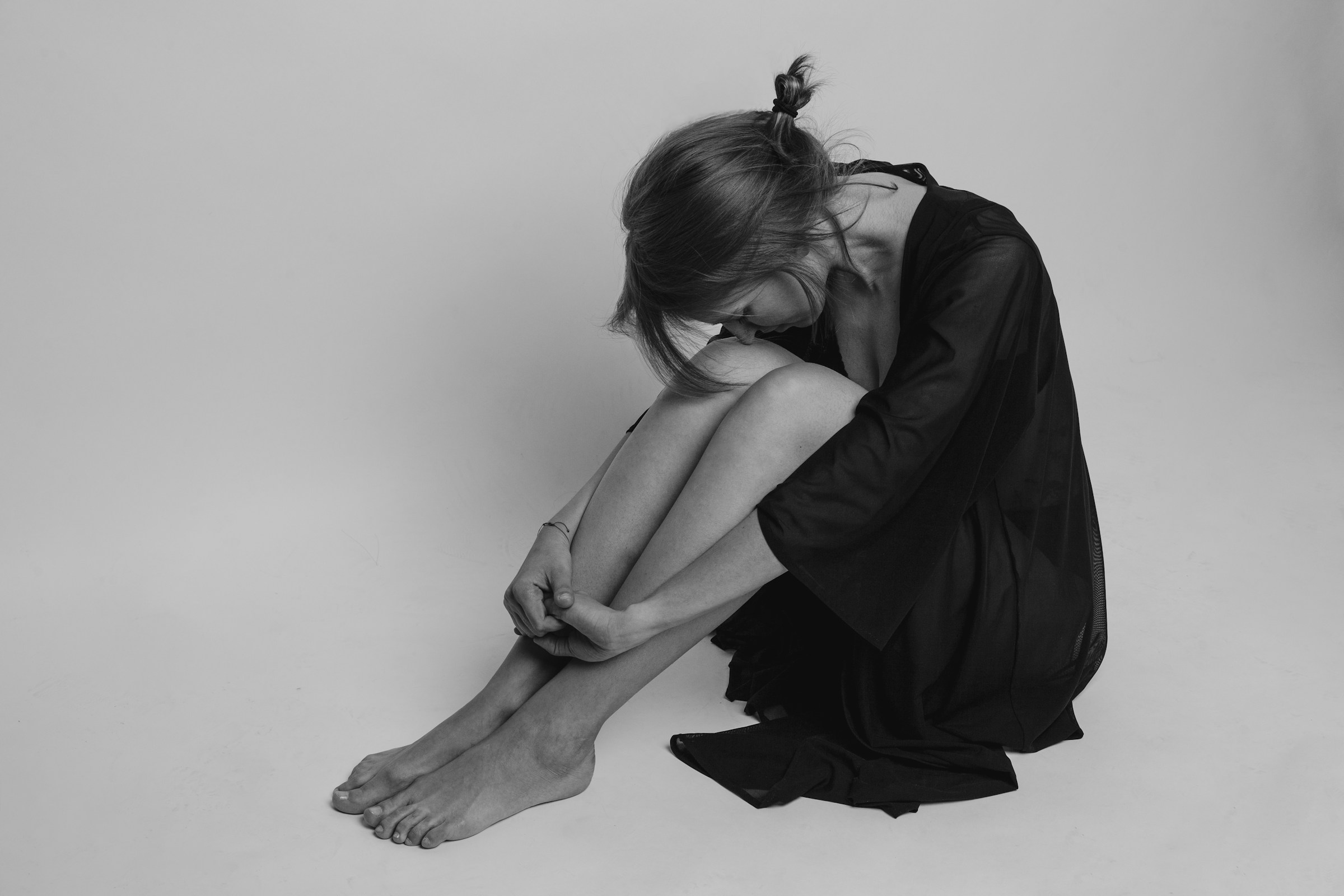 Girl in a black dress with her head on her knees